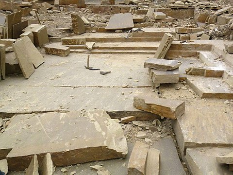 Split sandstone slabs and hand tools on the quarry floor